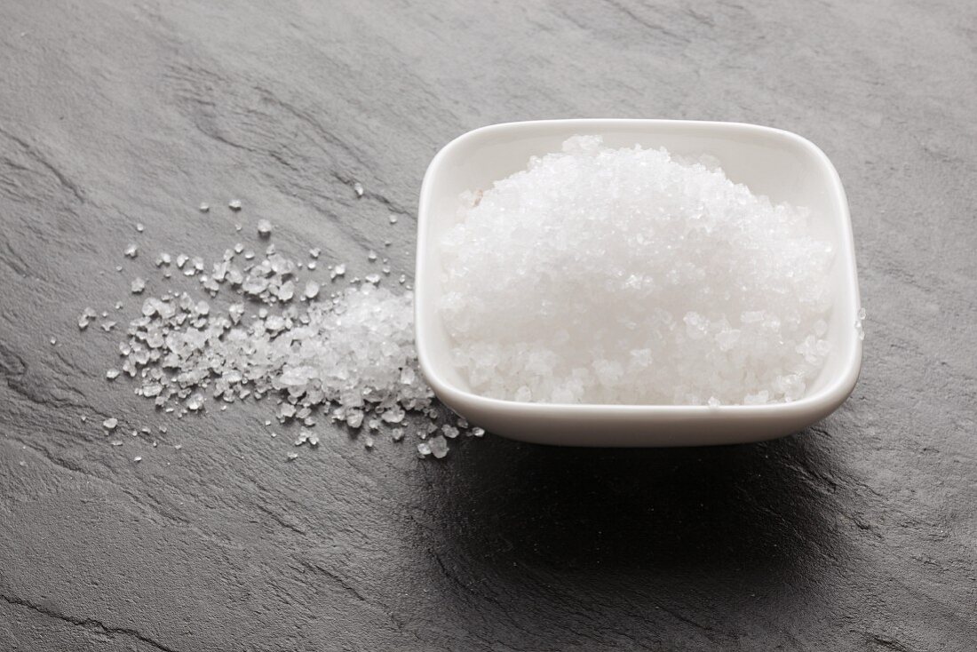 Fleur de sel in a bowl and on a slate surface