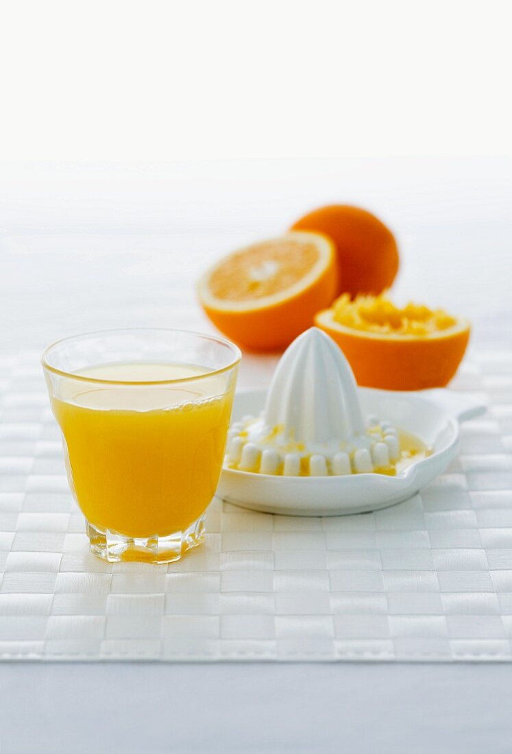 Ein Glas Orangensaft, Zitruspresse und Orangen
