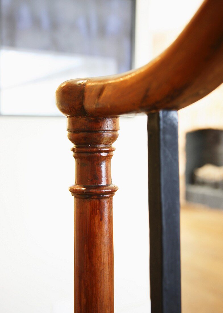 Antique, turned, varnished wooden newel post next to metal baluster