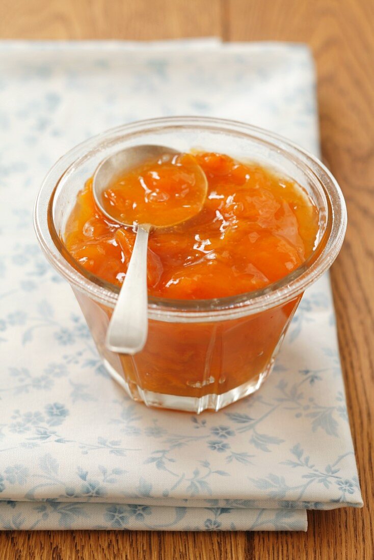 A jar of apricot jam with a spoon