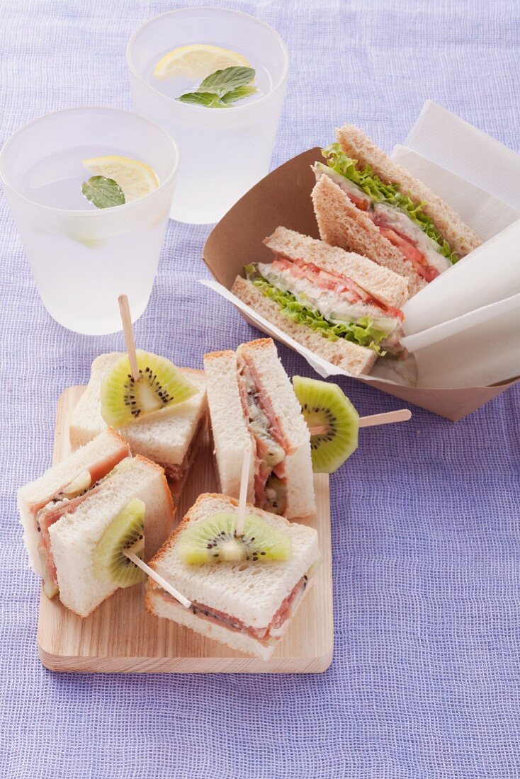 Whole wheat sandwich with tuna fish and finger sandwiches with Parma ham and kiwi