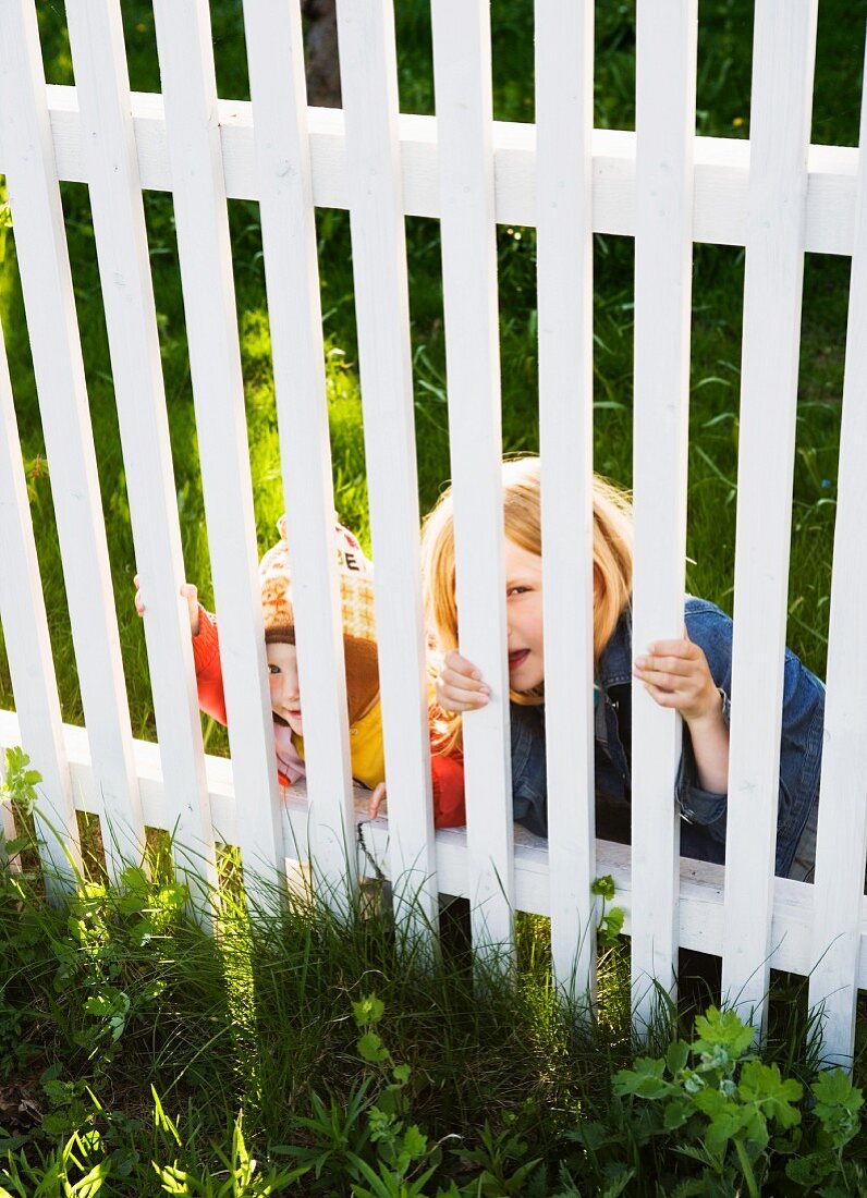 Kinder schauen durch den Gartenzaun