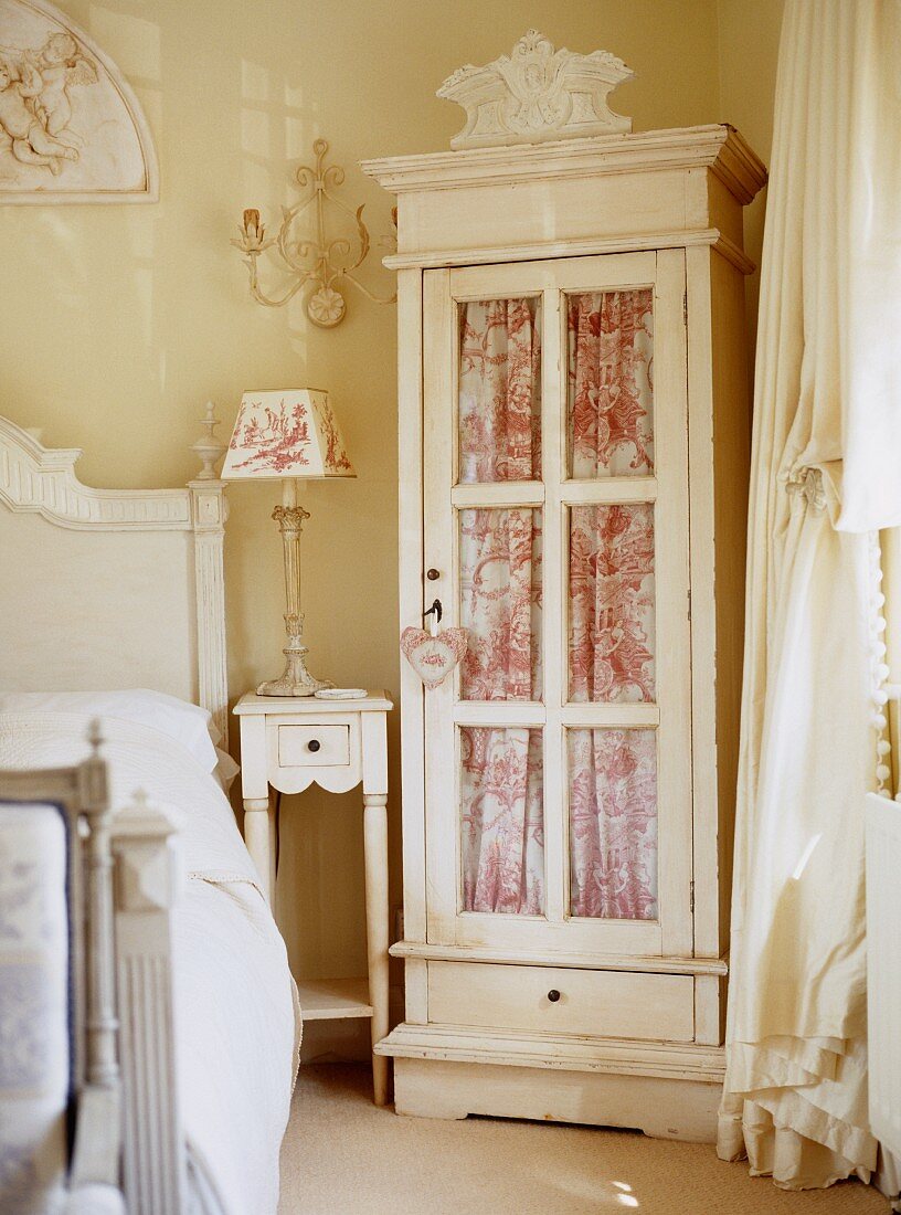 Glass-fronted cabinet with curtain in traditional, romantic bedroom
