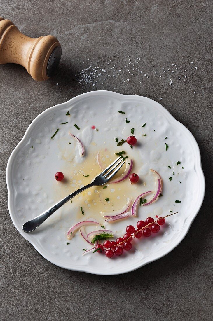 Reste von Salat und rote Johannisbeeren auf Teller