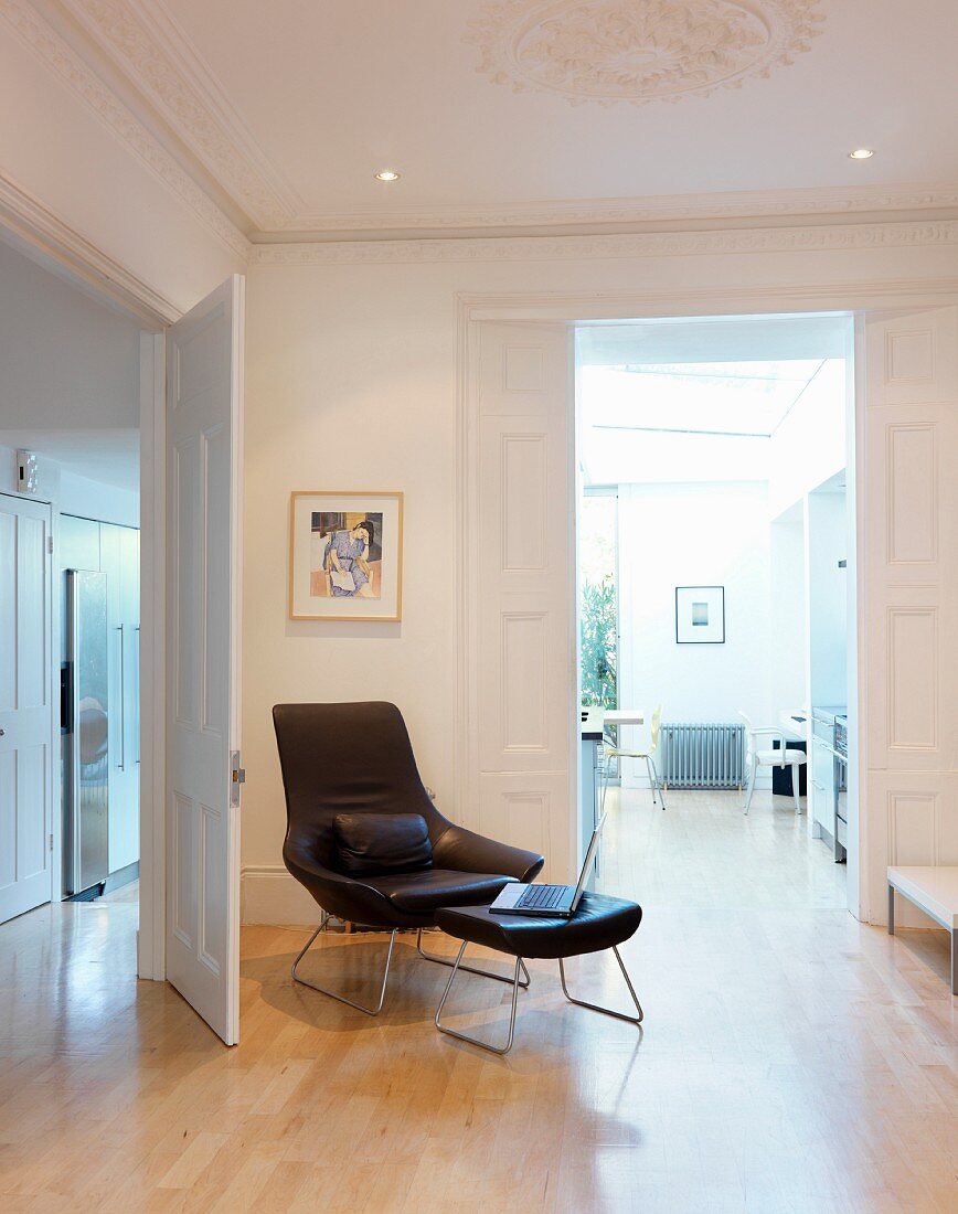 Designer leather armchair and matching footstool in traditional anteroom