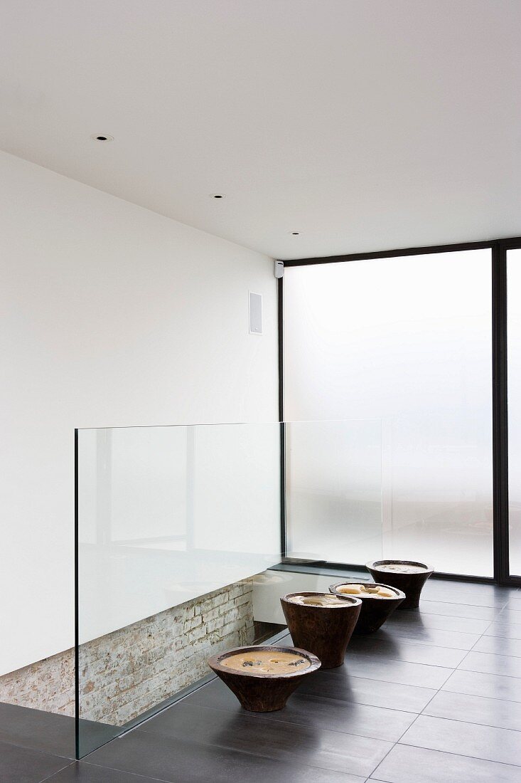 Contemporary hall with ceramic pots against all-glass balustrade of stairwell