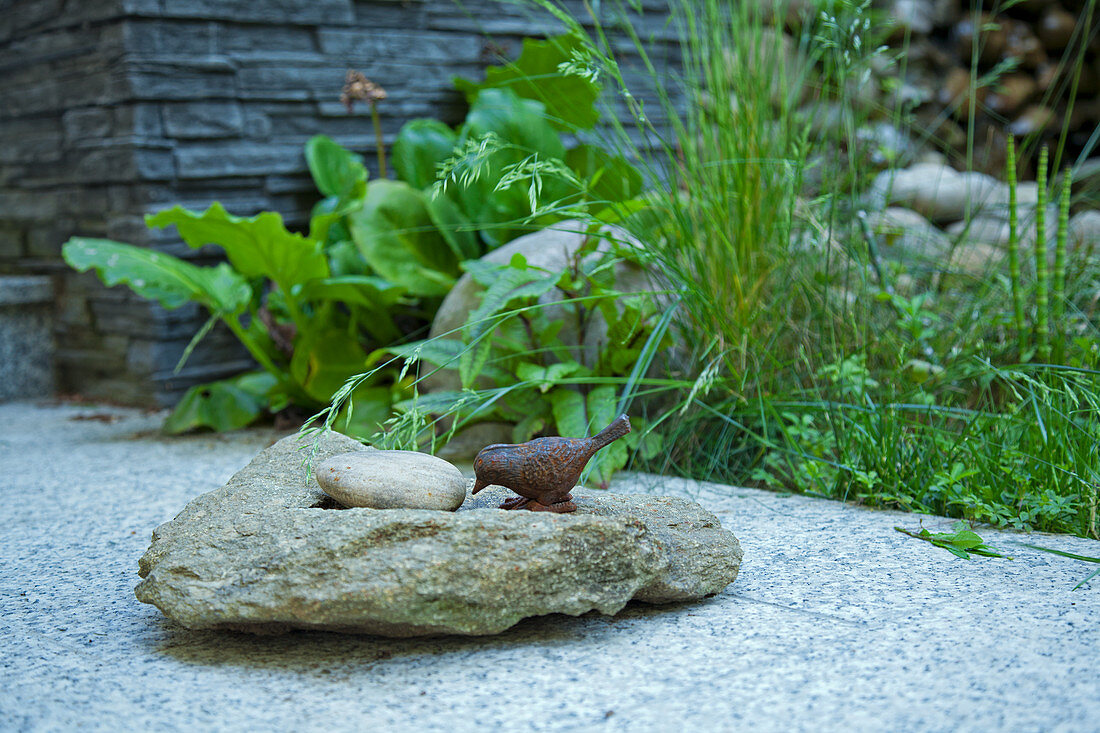 Stones and metal bird figurine on stone-flagged terrace