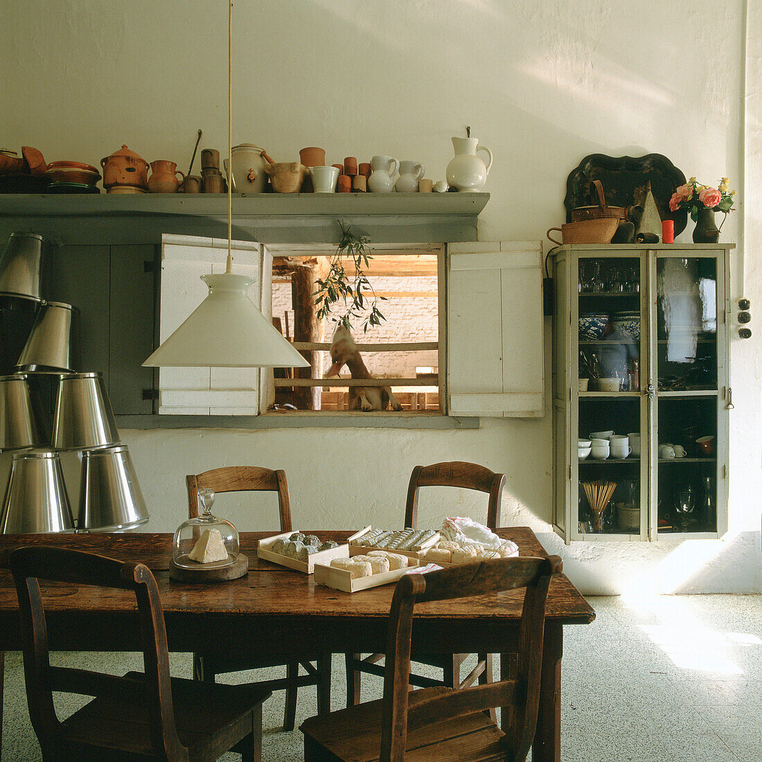 Holztisch und rustikale Regale mit Geschirr in der Landhausküche