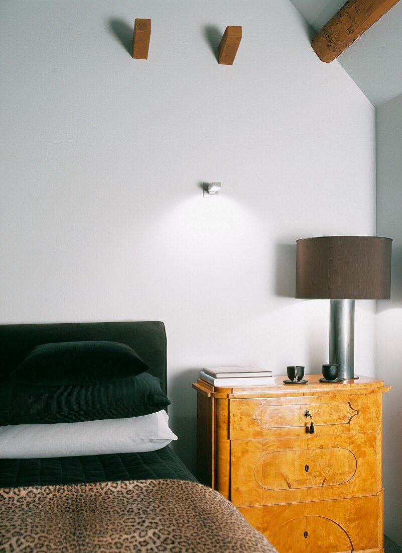 Biedermeier-style bedside cabinet with modern bedside lamp next to bed