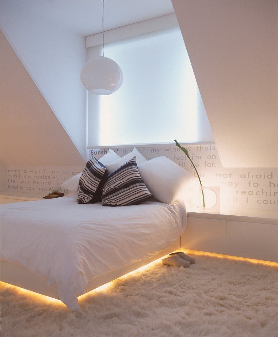 Double bed and sideboard with integrated, indirect lighting in modern attic room