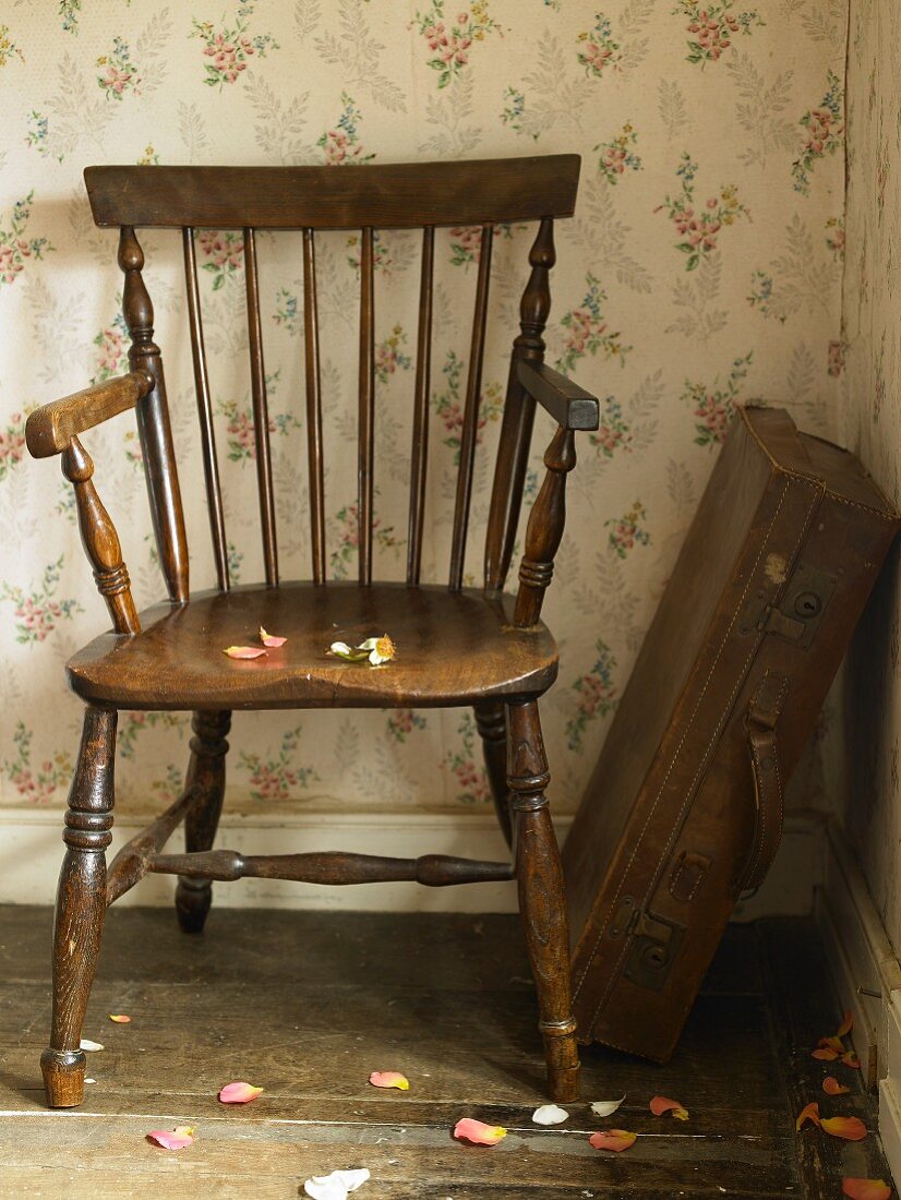 Antique wooden chair and old suitcase in corner