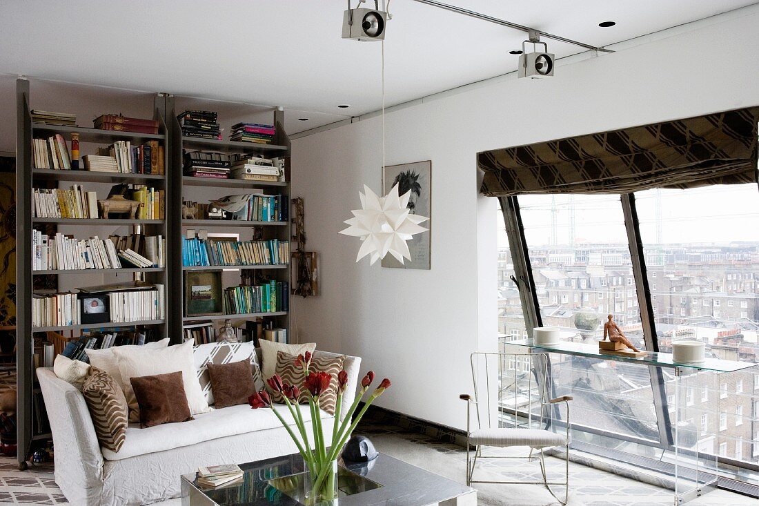 Youthful, modern living room with view of cityscape through slanting panoramic window