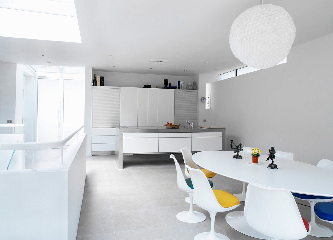 Open-plan room with minimalist kitchen and white dining area in designer retro style