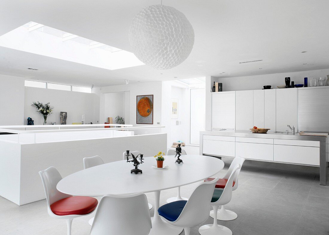 Modern designer kitchen and dining area with fifties retro furniture in open-plan white room