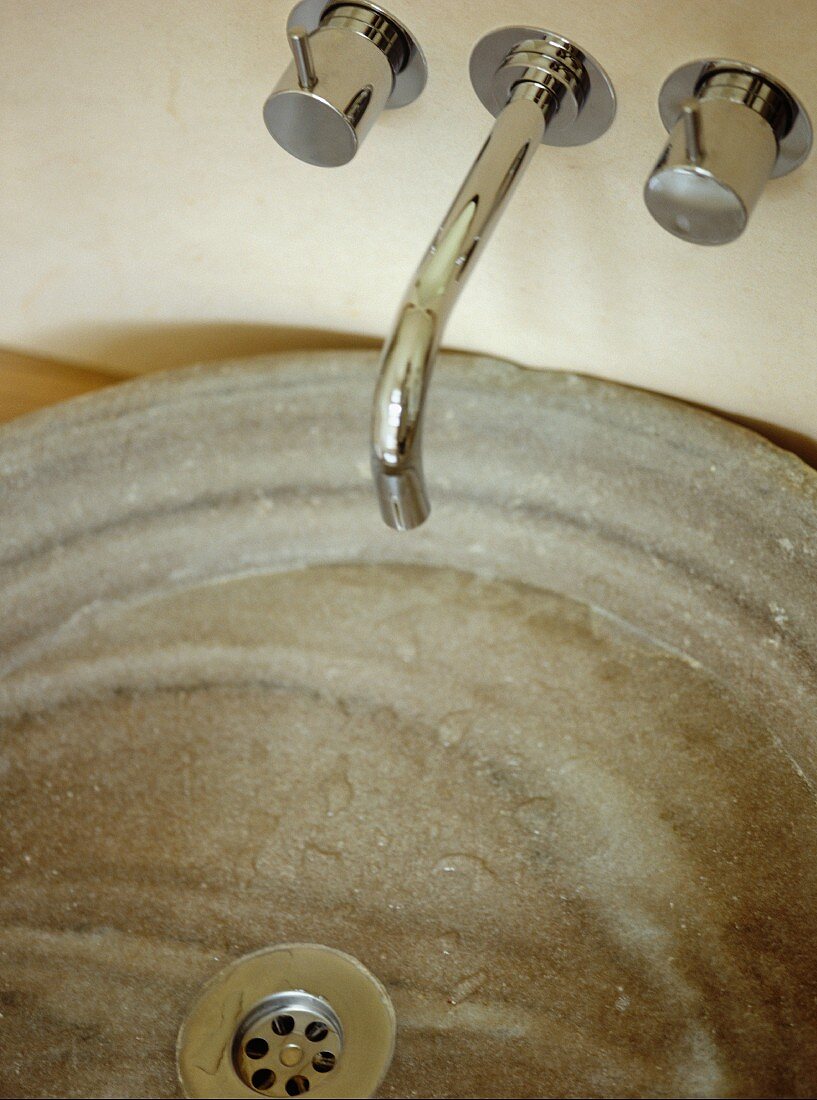 Moderne Wandarmatur über runder Waschschüssel aus Naturstein