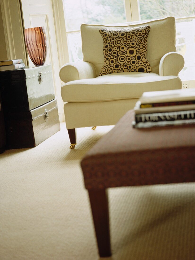 Light, upholstered armchair on castors with circle-patterned cushion in elegant contemporary living room