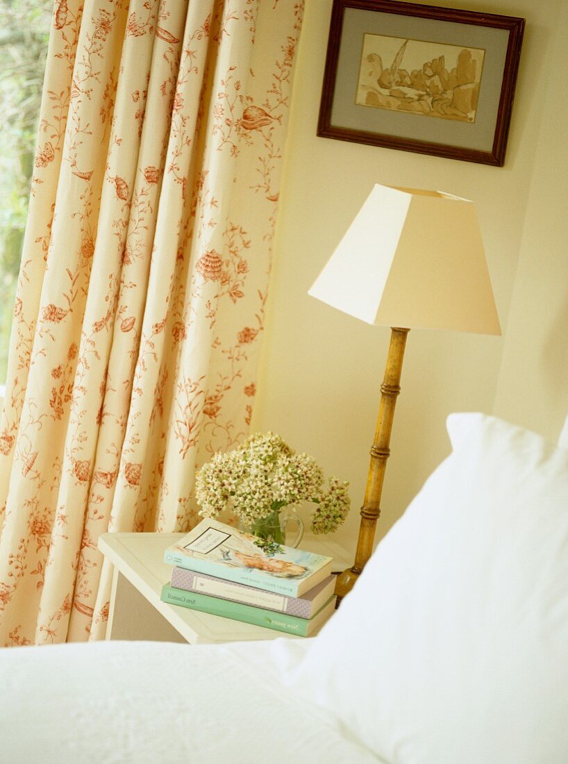 Bedside lamp with slender bamboo base in corner of romantic bedroom
