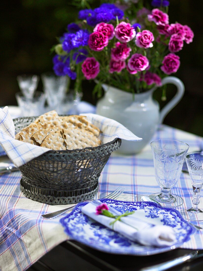 Gedeckter Tisch mit Brotkorb und mit Blumenstrauss