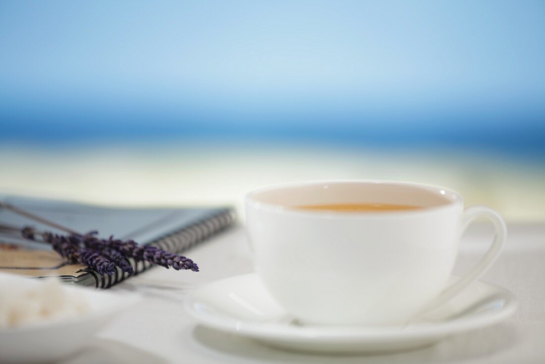 Eine Tasse Kaffe, im Hintergrund das Meer