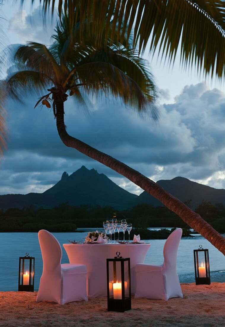 Table set for two on beach at dusk (Mauritius)