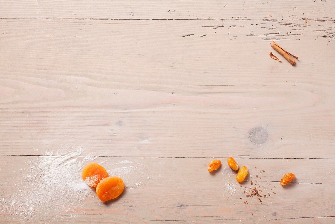 Dried apricots, dates and cinnamon stick on wooden background