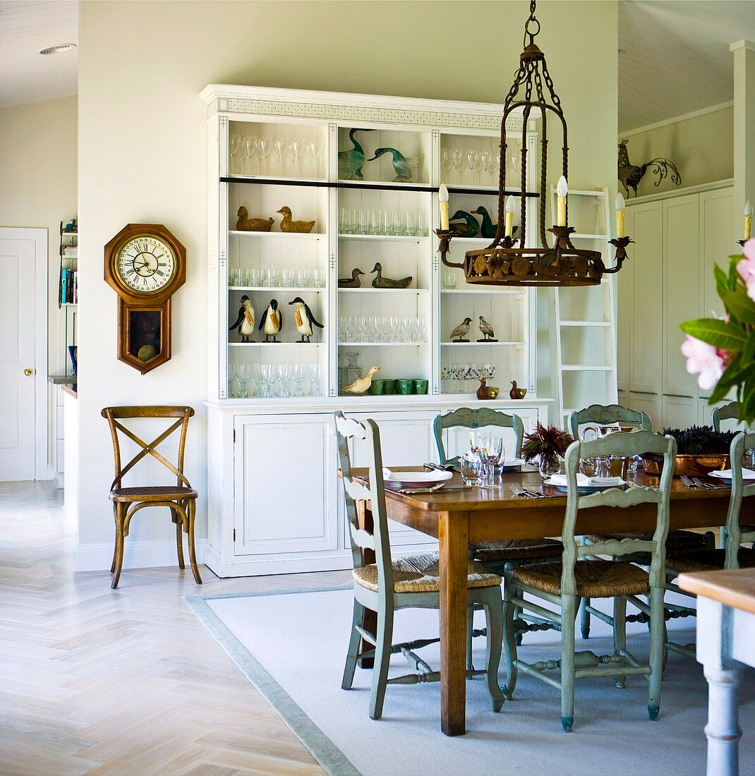 Chandelier hanging above set table in front of dresser against partition in rustic dining room