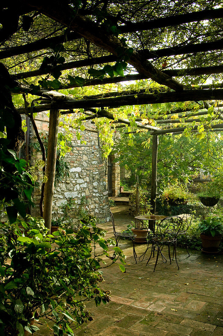 Terrace area under a pergola in front of a Mediterranean natural stone house