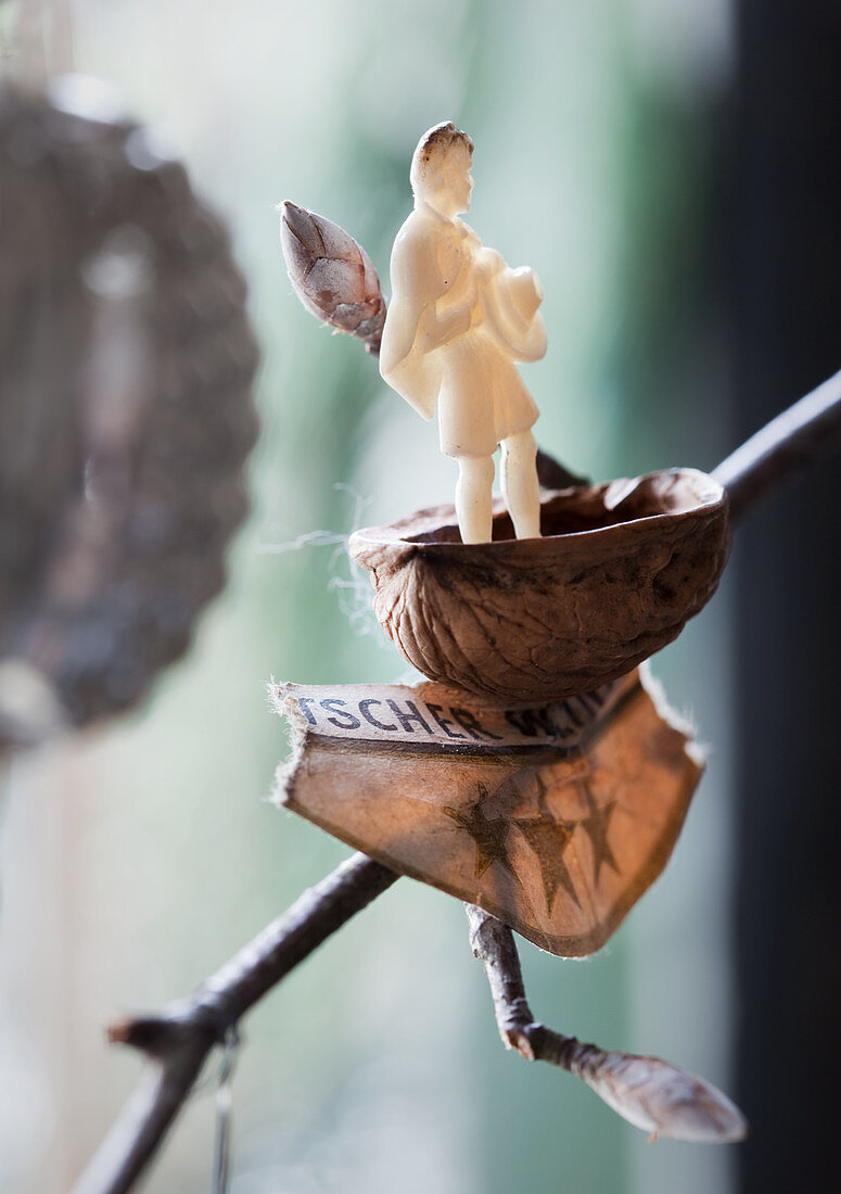 Miniaturfigur in einer Nusschale auf einem Zweig