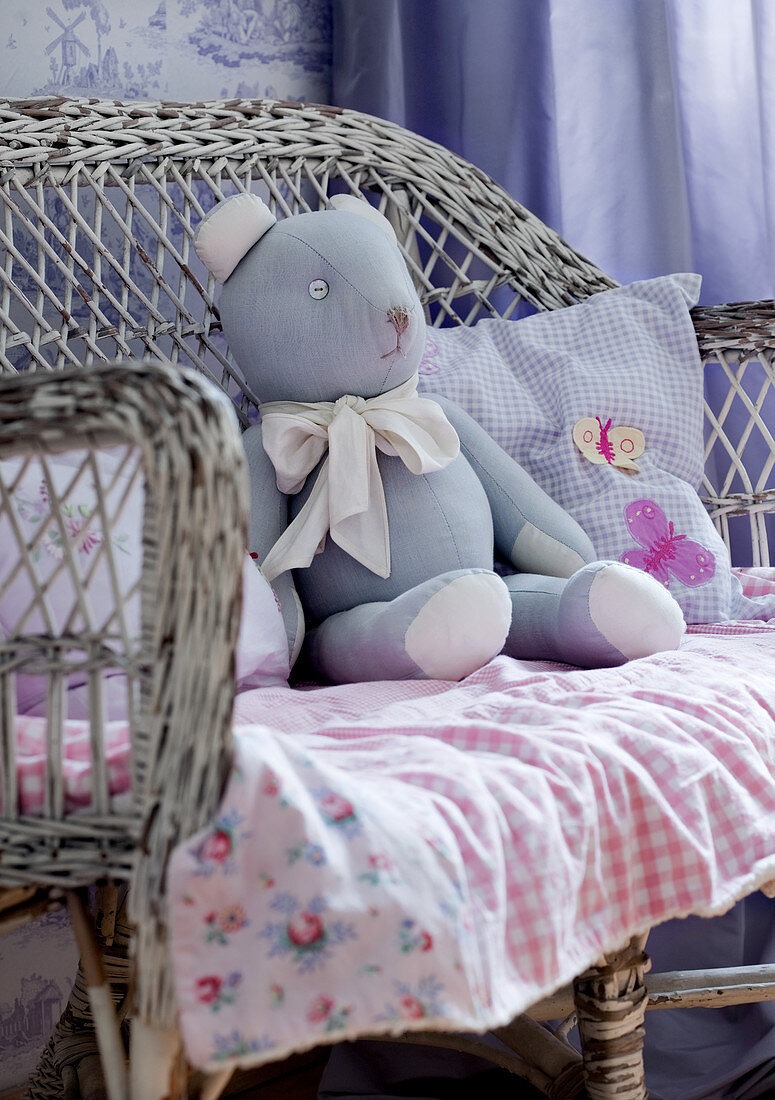 Teddy bear on gingham blanket on old wicker chair