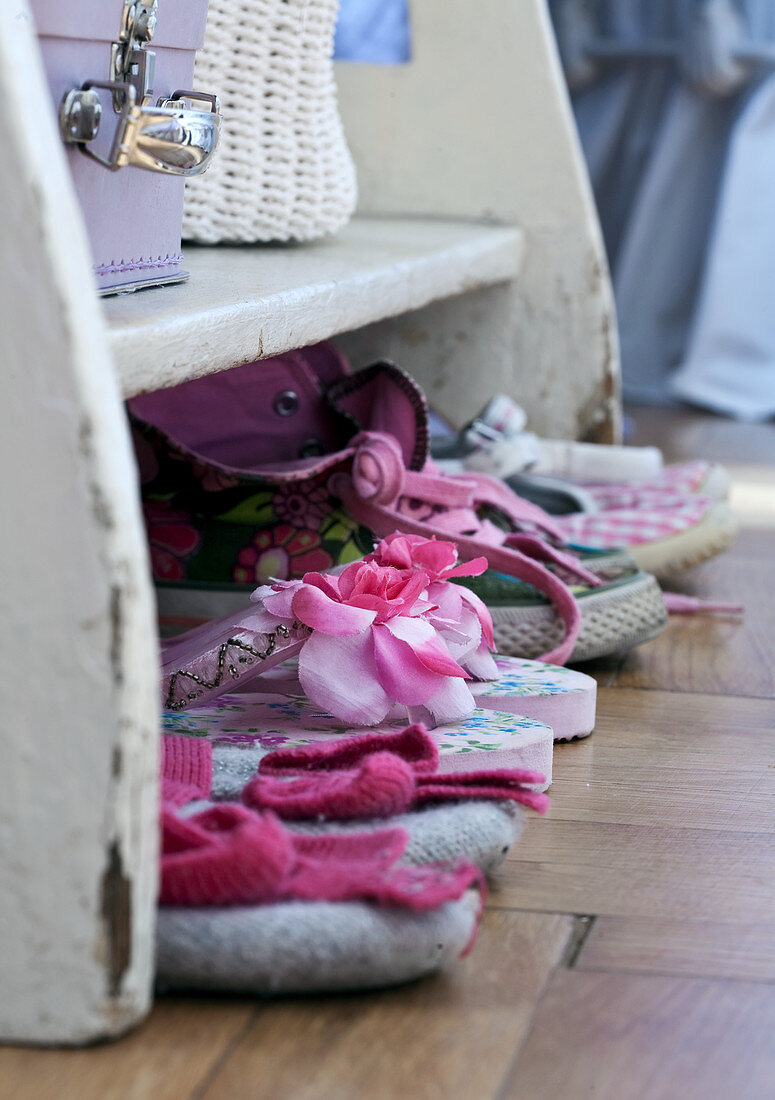 Children's shoes on parquet flooring in front of white shelves