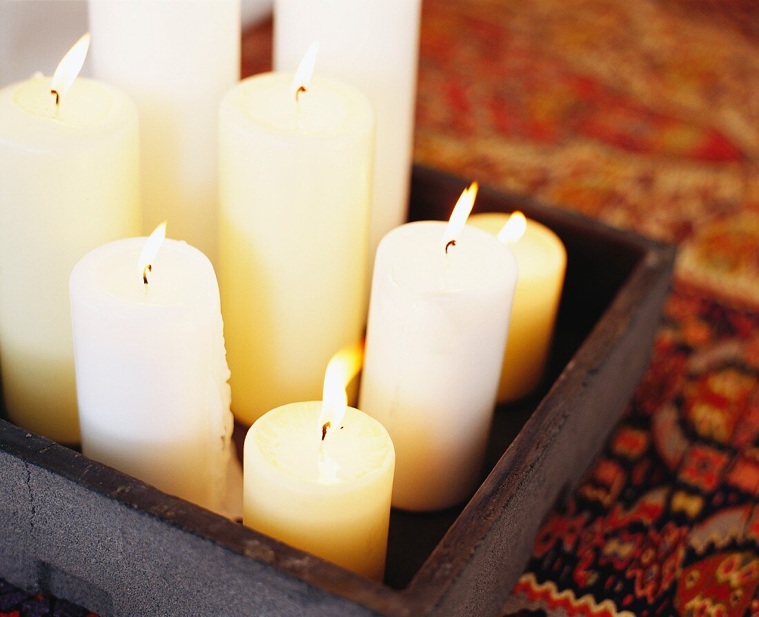 Burning candles in assorted sizes on a wooden tray