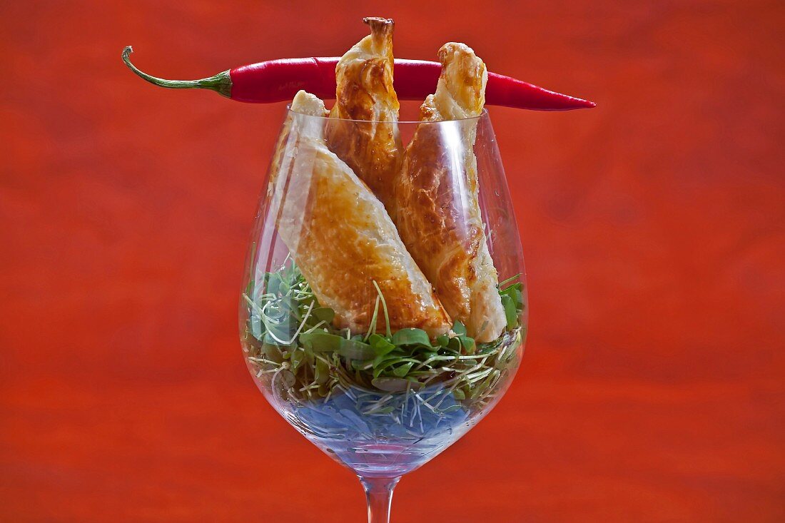Puff pastry twists with cheese filling on a bed of cress with a chilli pepper