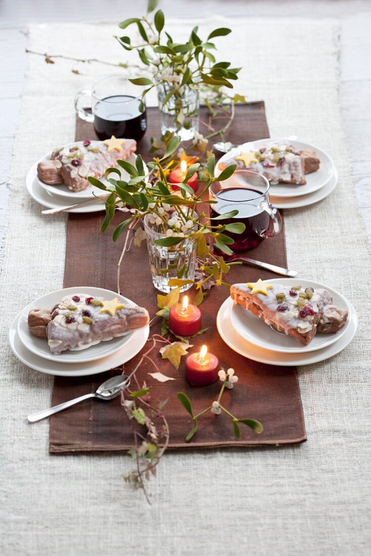 Christmas table with mistletoe, mulled wine, candles and iced Christmas tree cakes