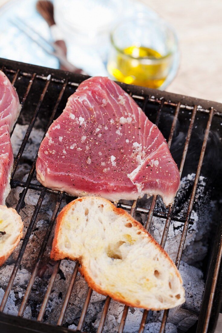 Tuna steak and a slice of baguette on a grill