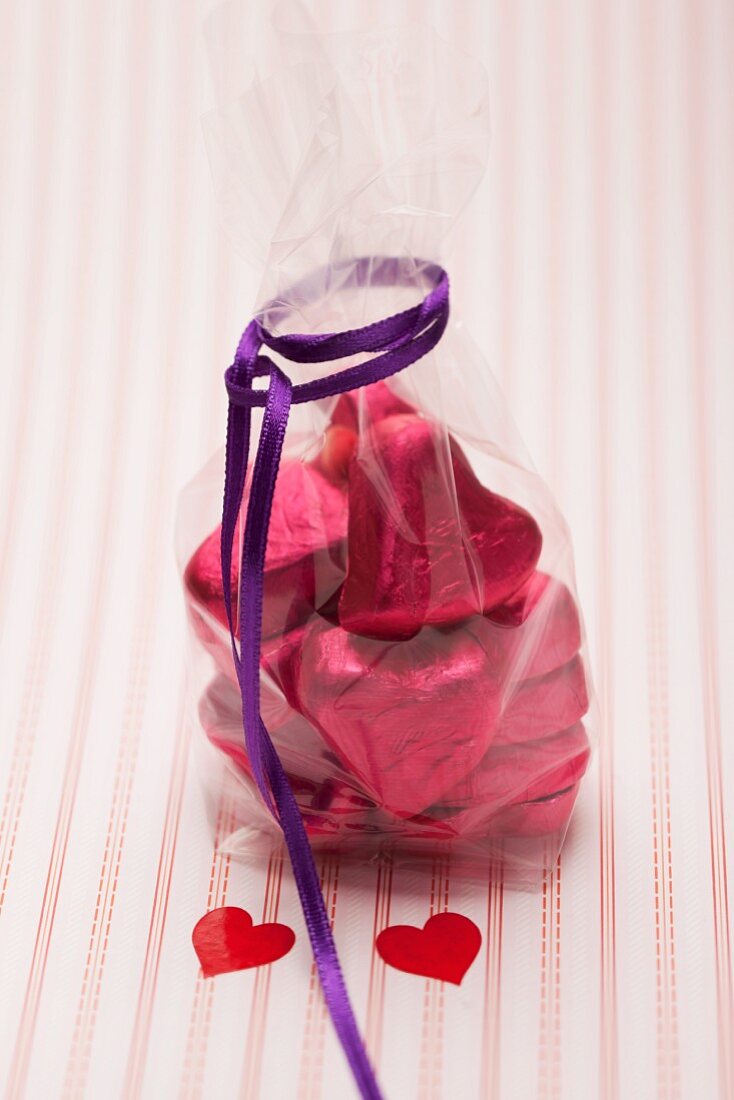 Heart-shaped chocolates wrapped in red foil in a cellophane bag