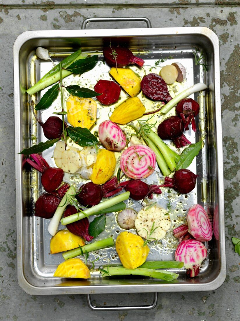 Various types of beetroot and spring onions in a roasting tin