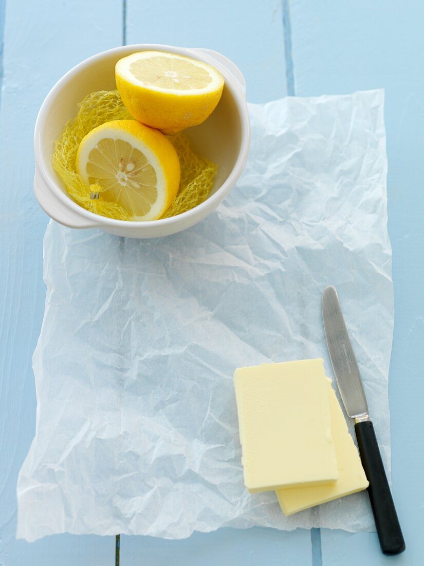 Butter auf Brotpapier und Zitronenhälften in einer Schüssel