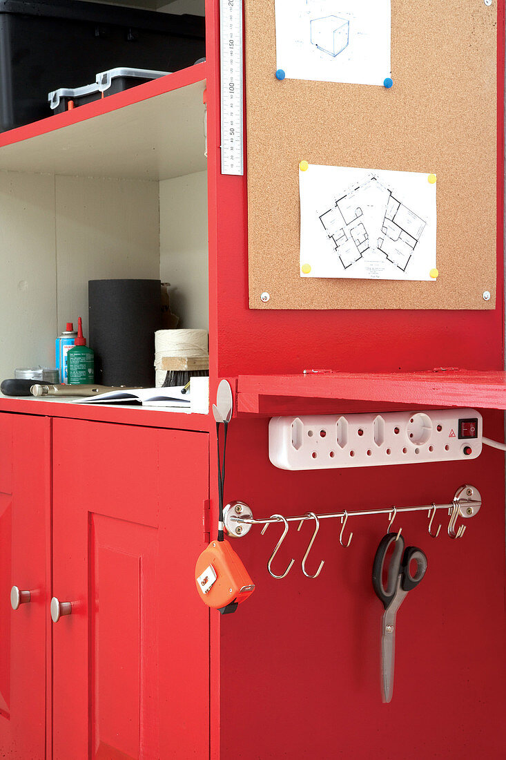 Red tool cabinet with pinboard, attached workbench, multiway power strip and hook rail
