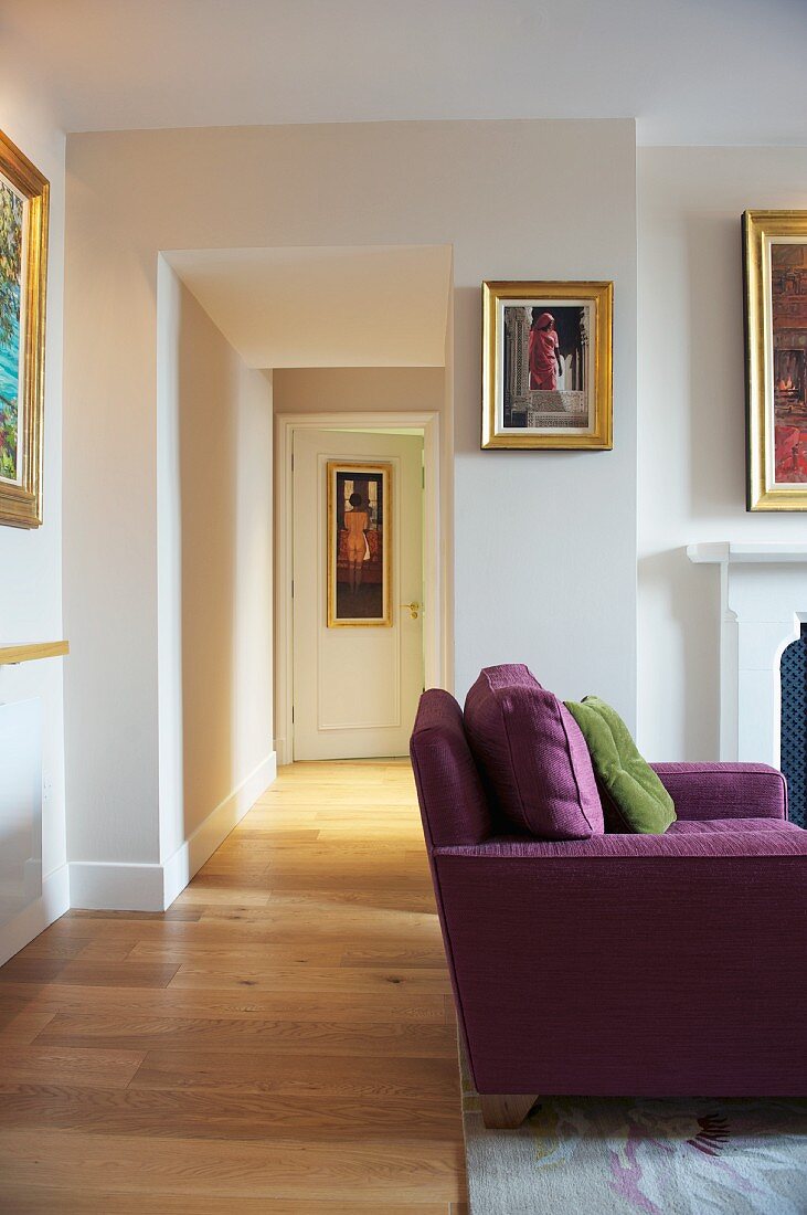 Purple sofa in living room with open doorway and view of hall