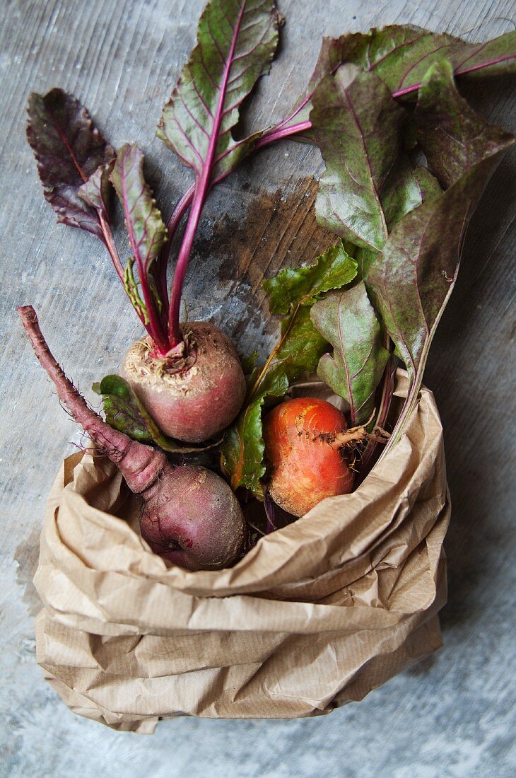 Red and yellow beets in brown paper bag