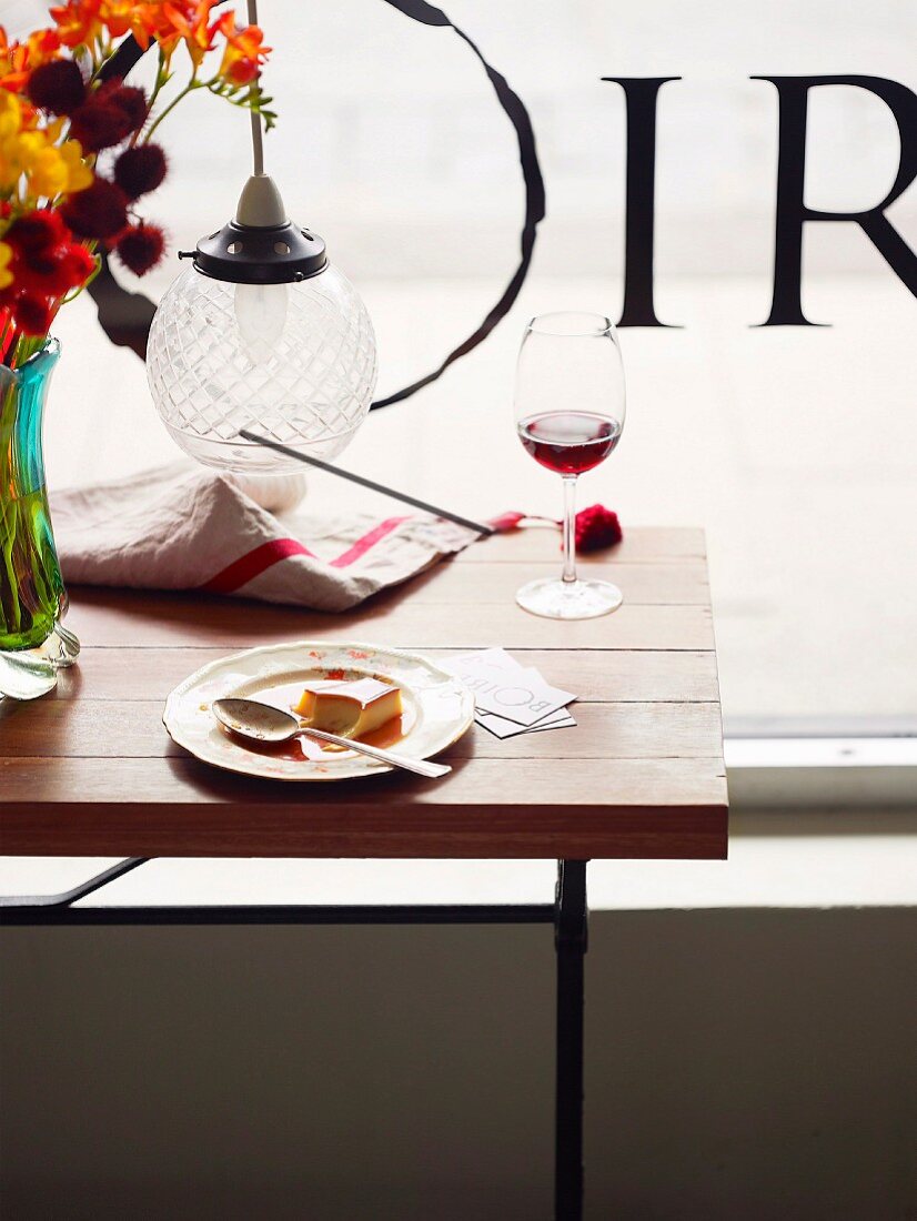 Crème Caramel und Rotweinglas auf Tisch im Lokal