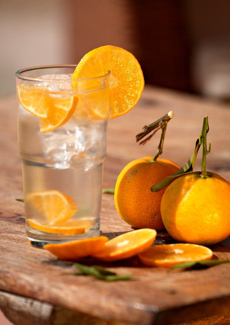 Water glass with ice cubes and tangerines