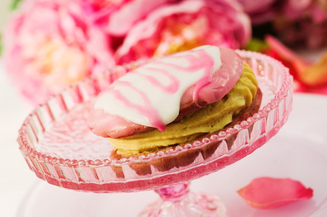 Whoopie pie with butter cream on a cake stand in front of peonies