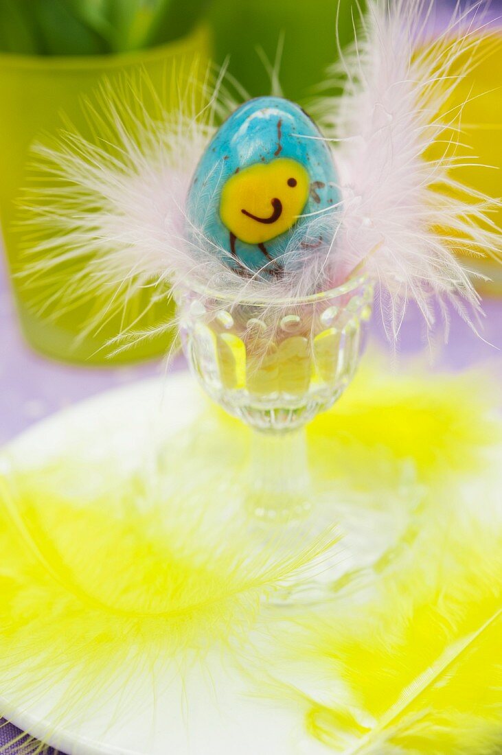 Painted Easter egg with feathers in an egg cup