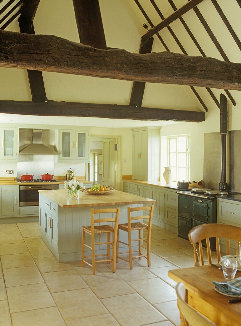 Kitchen island with bar stools in open-plan kitchen of country house with half-timbered structure