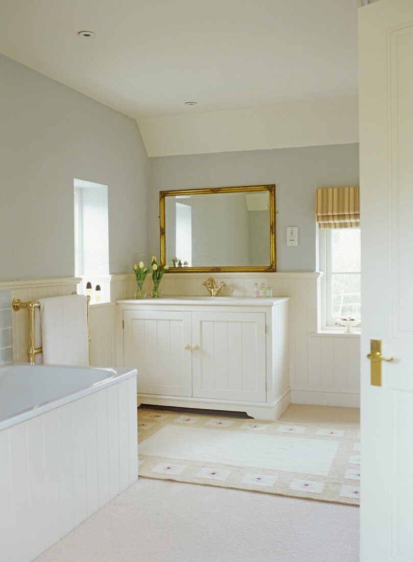 View of white-painted, wooden washstand in country-style bathroom through open door