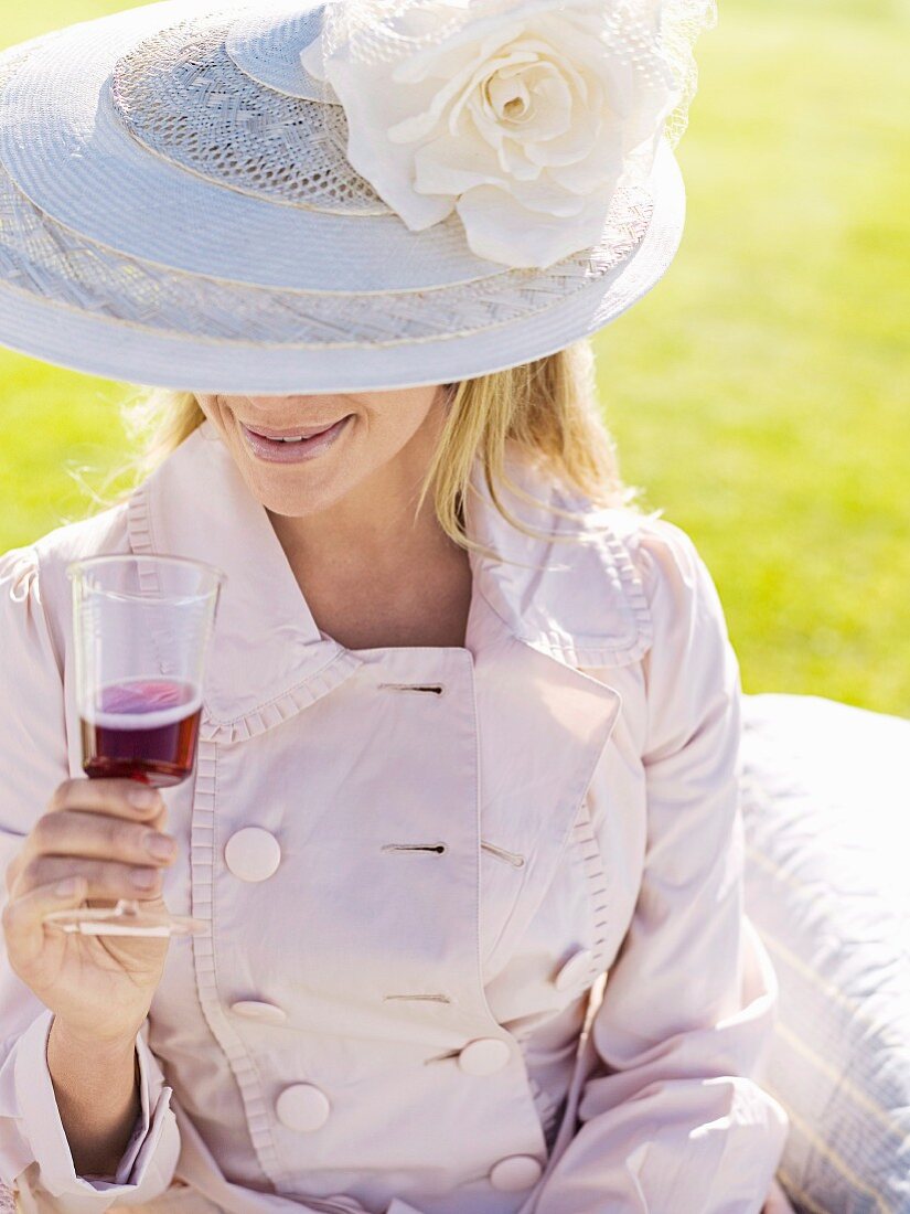 Frau mit Hut trinkt ein Glas Rotwein