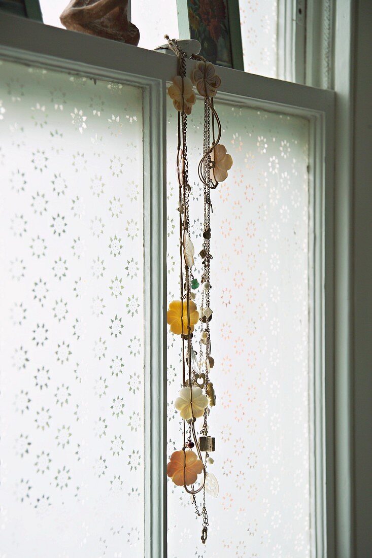 Necklace with flower motif hanging in front of window