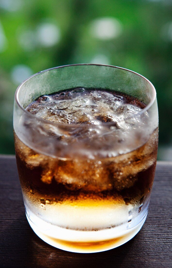 Glass of Soda with Ice on an Outdoor Railing; Ice Melting