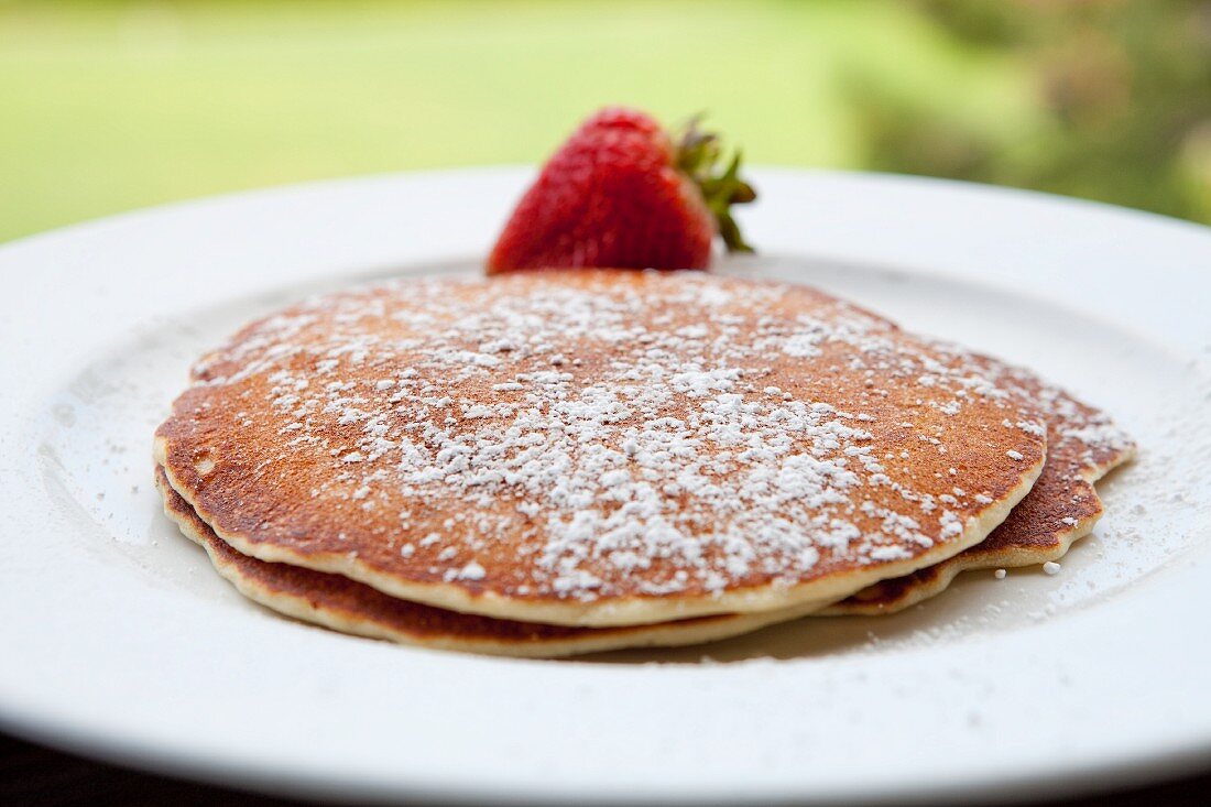 Pancakes with Powdered Sugar and a Strawberry; Outdoors